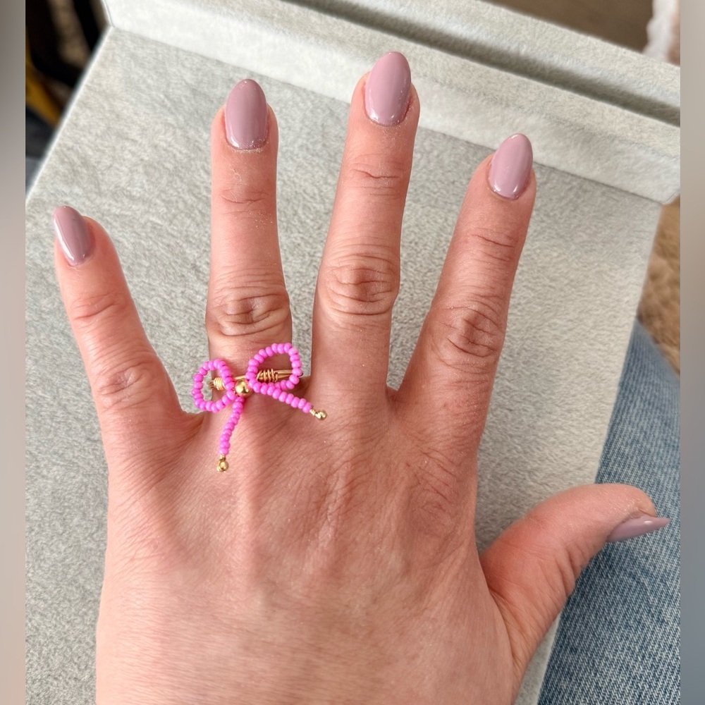 Stainless steel ring with a pink beaded bow motif
Size 8